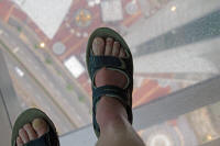 Tourist standing on observation window, 58th floor of Macau Tower